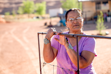 A Native elder outside, her arms adorned with turquoise bracelets. 