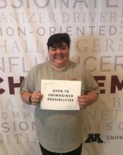 Karlena holds a sign that says "open to unimagined possibilities."